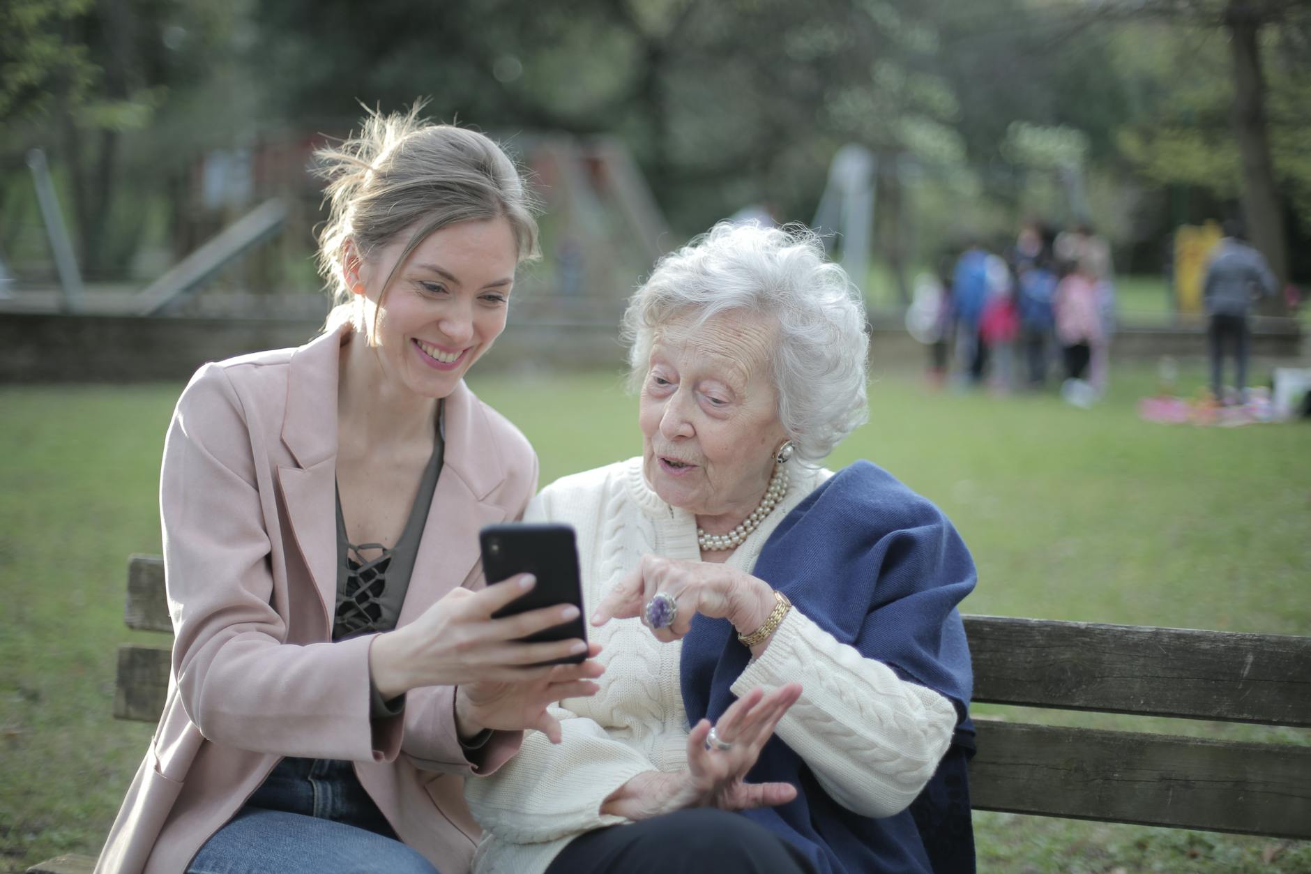 Delighted female relatives sitting together on wooden bench in park