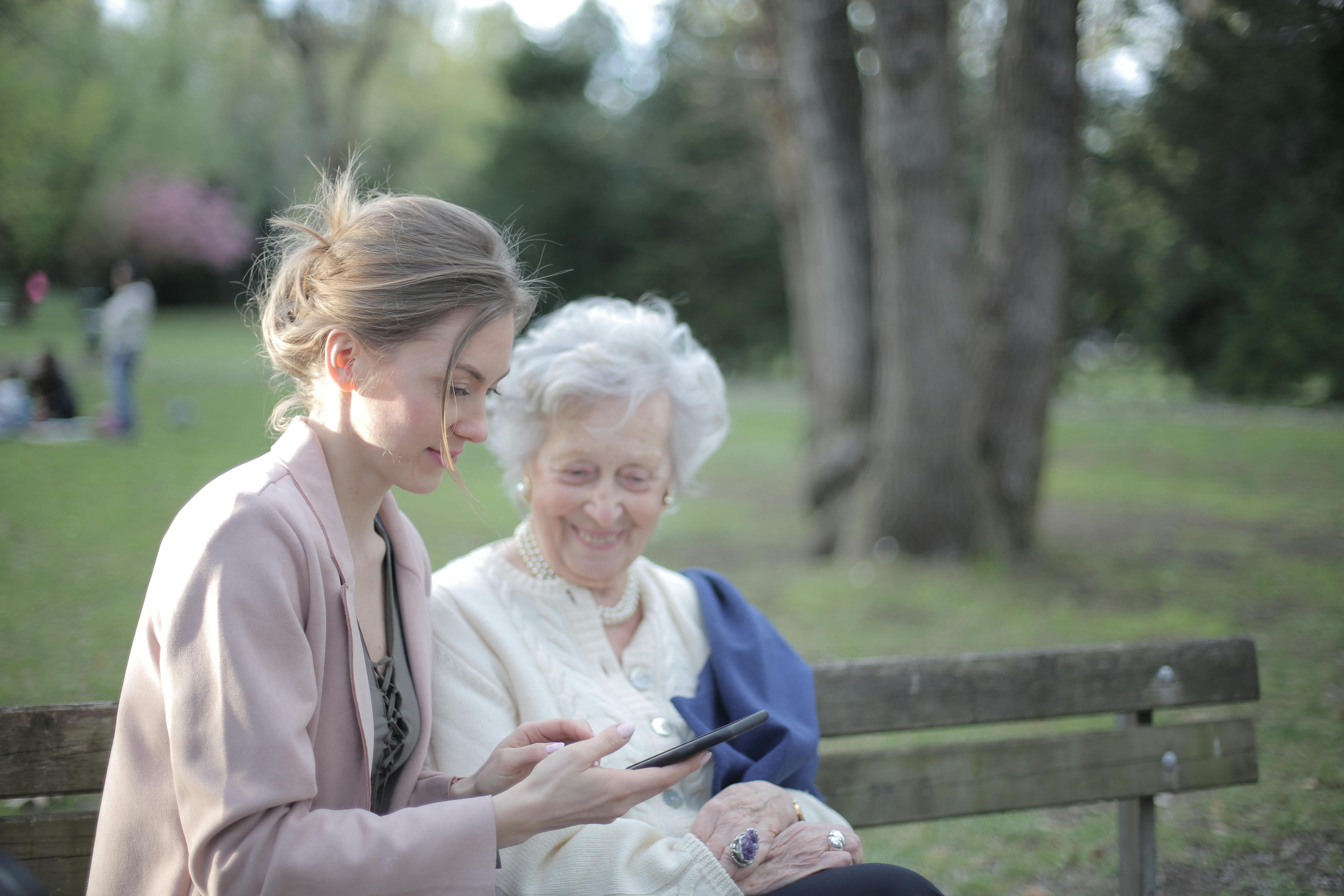 daughter explaining elderly mother how using smartphone