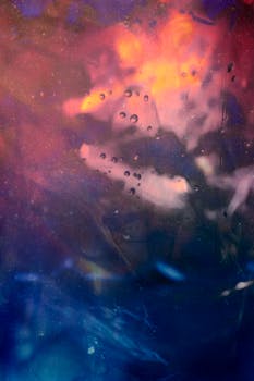 彩色玻璃上水滴的抽象图像充满活力，营造出日落般的视觉效果