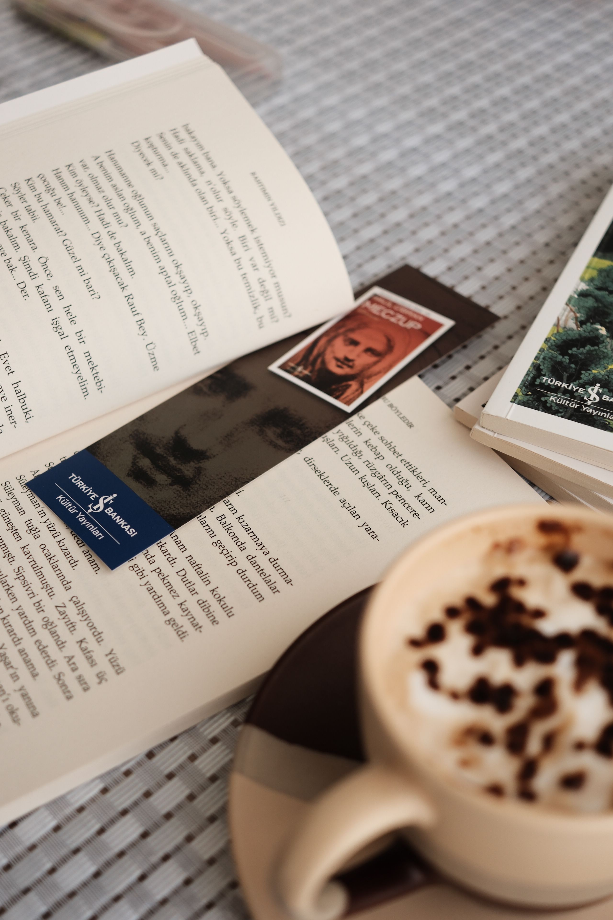 Open book with bookmark and coffee on a table, creating a cozy reading atmosphere.