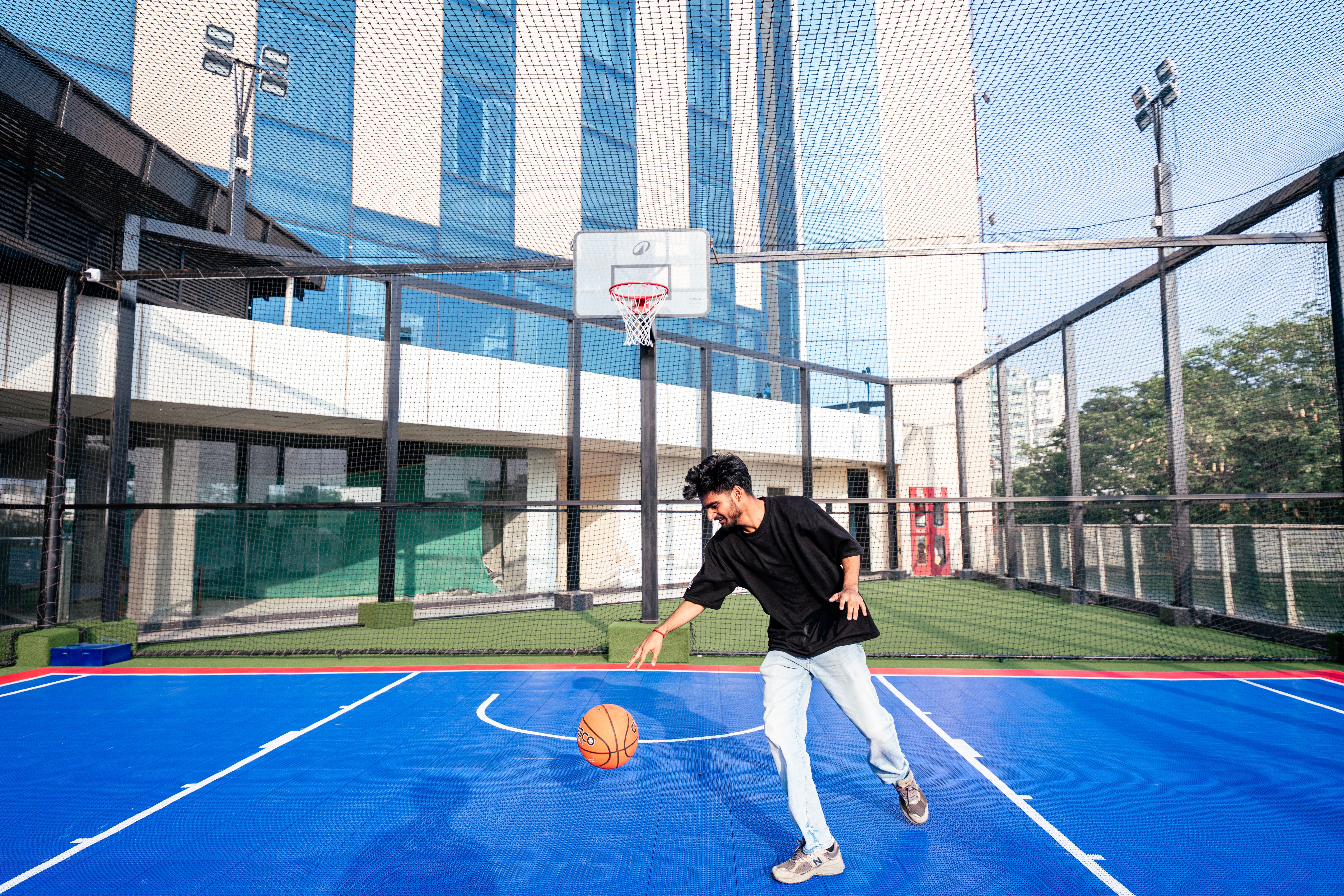 NCAA Basketball photo featuring Young man dribbling a basketball on a vibrant outdoor court in the city, showcasing active lifestyle and fitness.