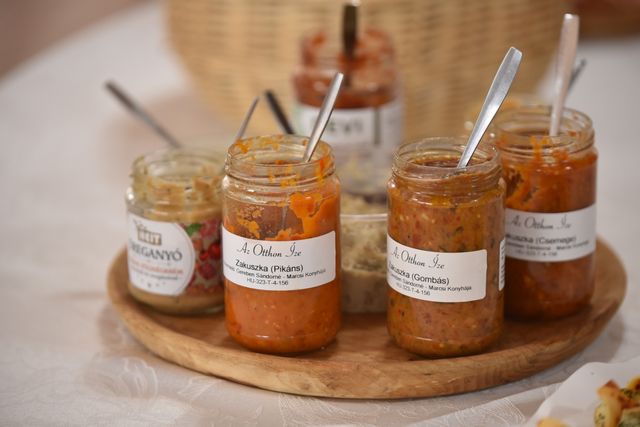 A selection of Hungarian vegetable spreads in jars on a wooden tray.