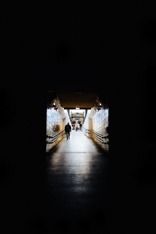 Фотография человека, идущего в темном туннеле