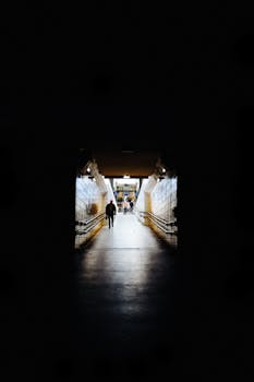 A dramatic view of a dimly lit subway tunnel with people walking, creating an urban atmosphere.