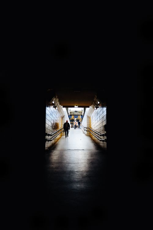 Free A dramatic view of a dimly lit subway tunnel with people walking, creating an urban atmosphere. Stock Photo