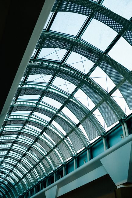 A detailed upward view of a glass roof with metal frame and geometric patterns.