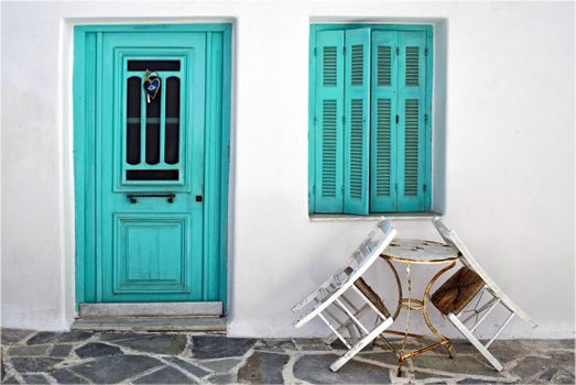 A picturesque turquoise door and window with rustic charm in Naxos, Greece, featuring traditional architecture.