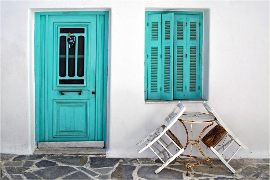 A picturesque turquoise door and window with rustic charm in Naxos, Greece, featuring traditional architecture.