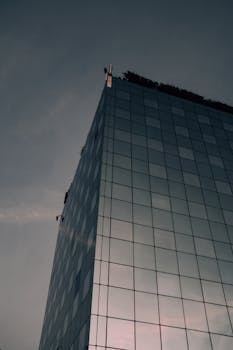 傍晚的天空映照在玻璃幕墙的摩天大楼上，展现了现代城市建筑的风貌