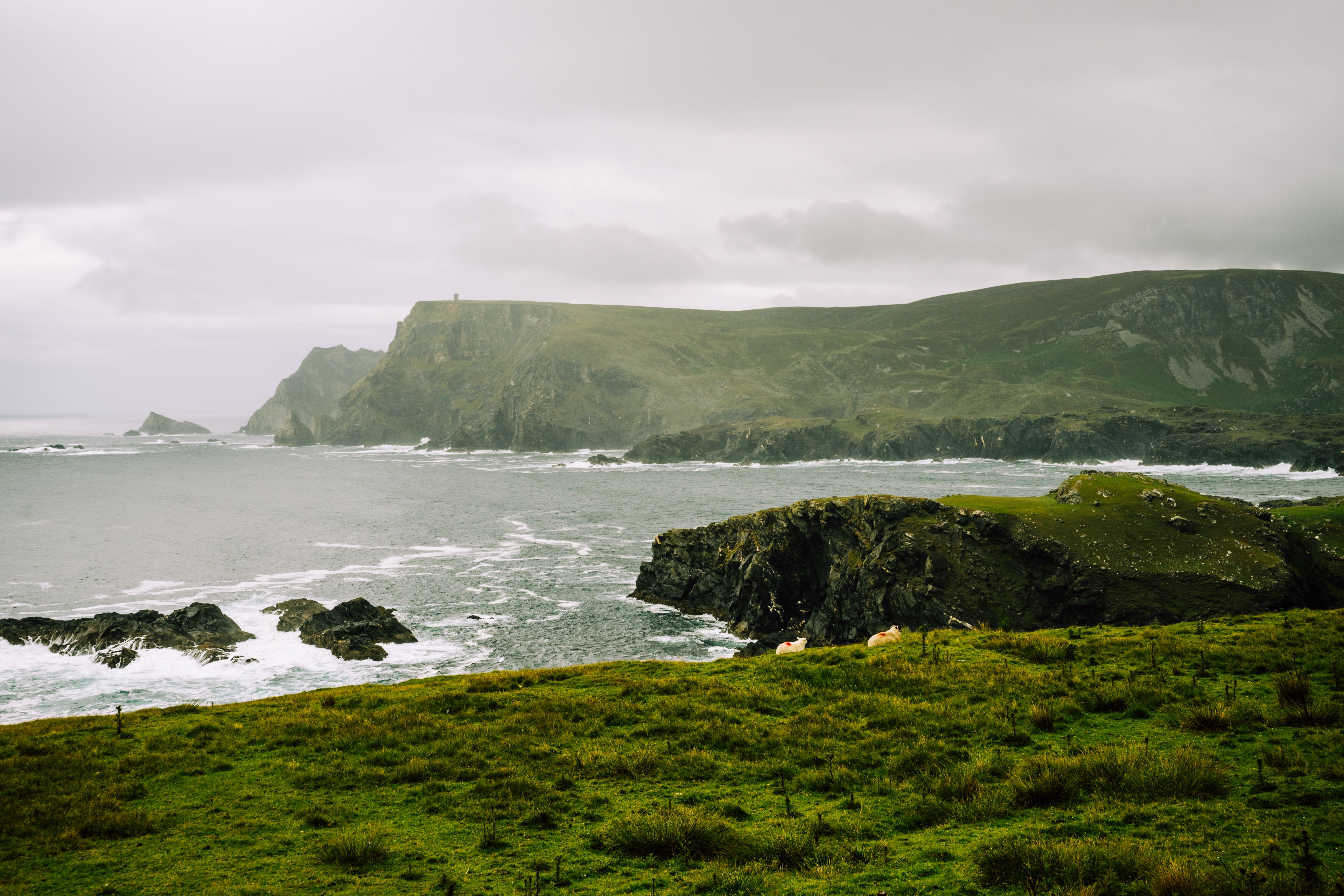 Rugged coastline with cliffs meeting the ocean under a moody sky, offering a scenic and dramatic view.