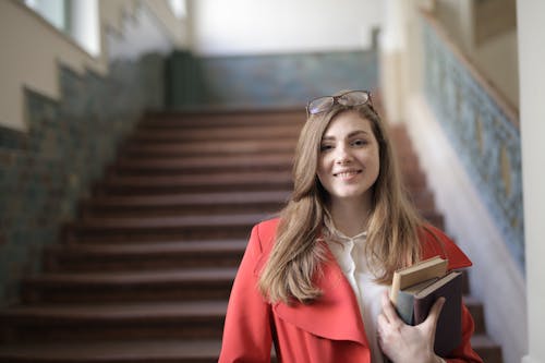 Free Woman in Red Blazer While Holding Books Stock Photo