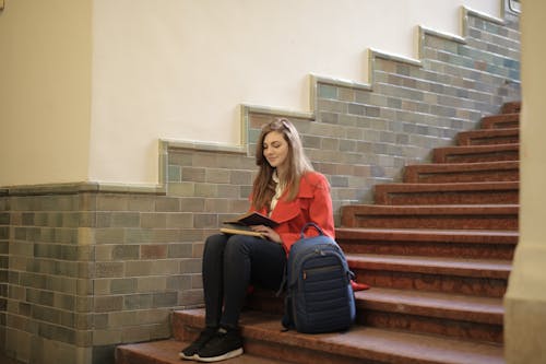 Woman Sitting on Staircase While Reading a Book