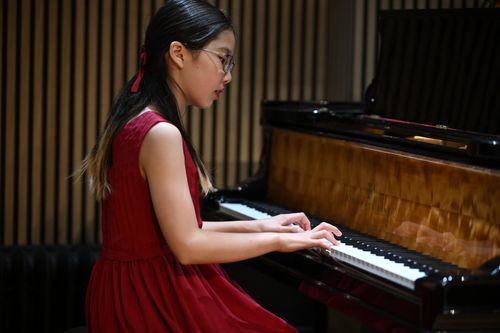 Free Young pianist in red dress passionately playing a grand piano in a New York concert hall. Stock Photo