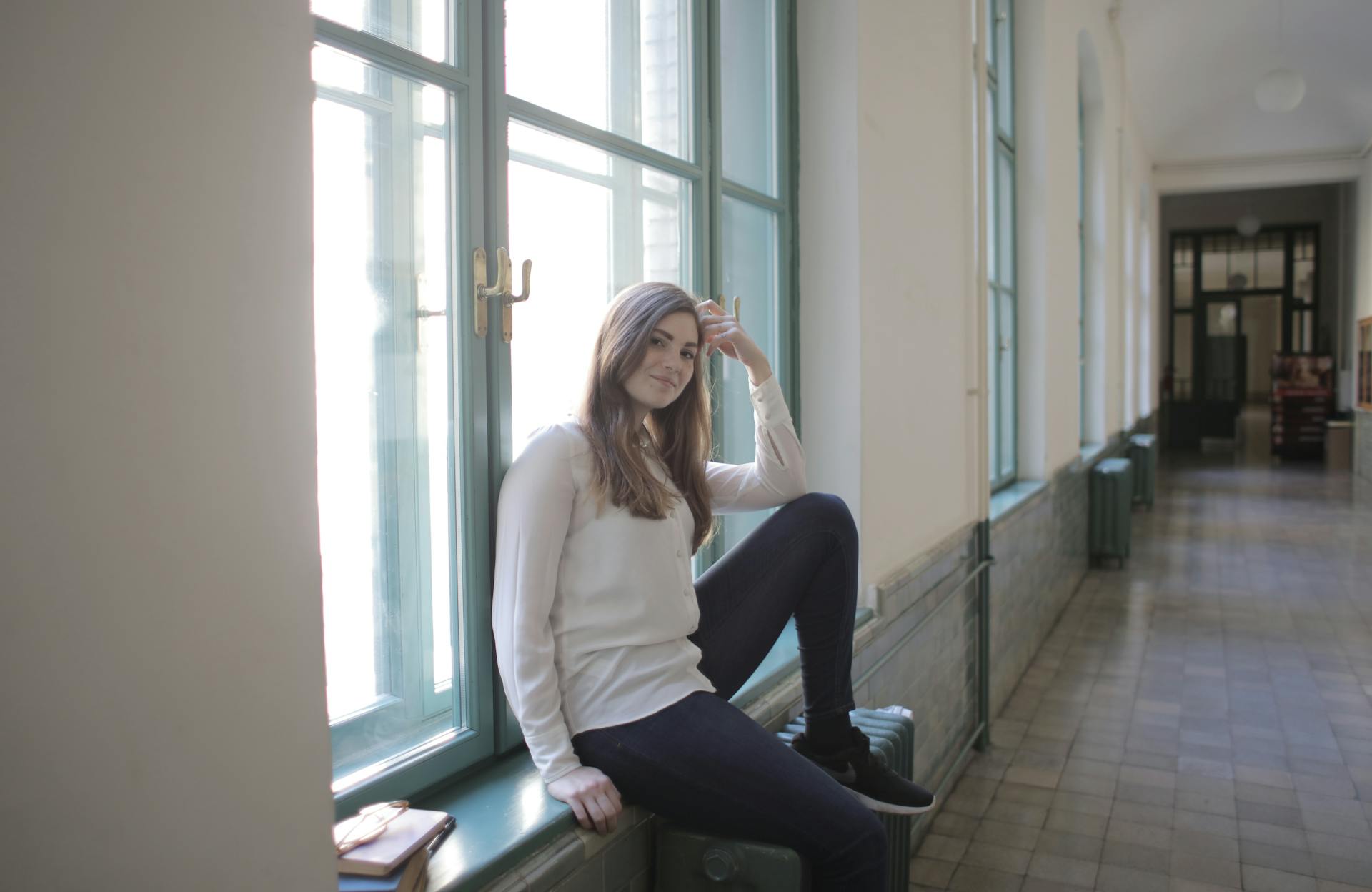 Young female student relaxing during break in university corridor