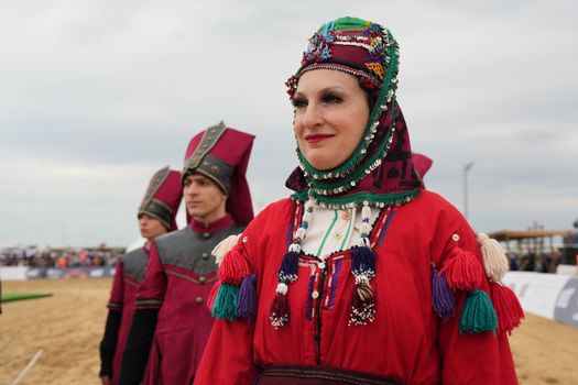 Participants in traditional costumes at cultural festival enjoying vibrant atmosphere outdoors.
