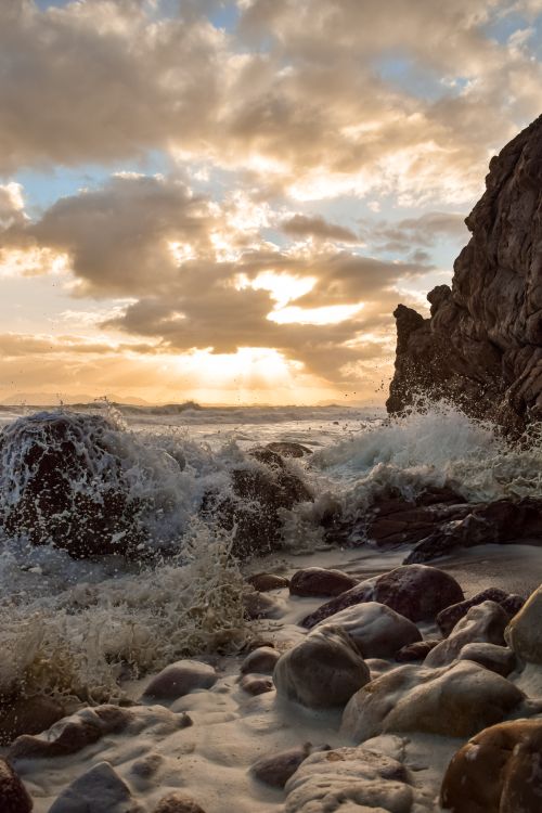 Free Waves crash against rock formations in Cape Town at sunset, capturing nature's raw beauty. Stock Photo