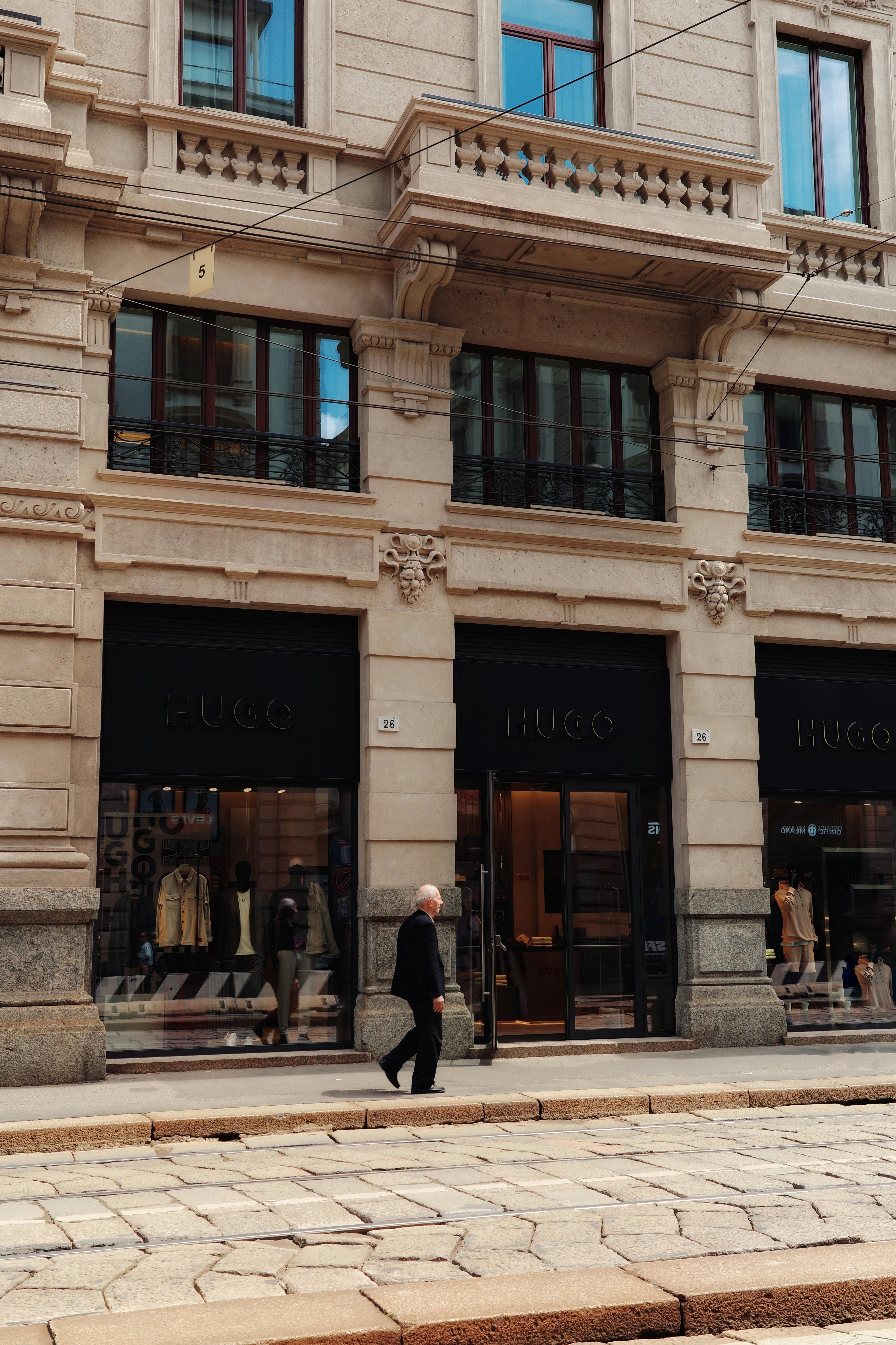 Elegant city street photo of a fashion boutique in Milan, Italy. A man walking past adds urban charm.