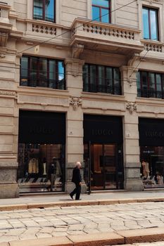 Elegant city street photo of a fashion boutique in Milan, Italy. A man walking past adds urban charm.