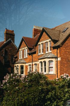 Quintessential brick architecture set amidst lush greenery in Oxford, UK, under a clear blue sky.