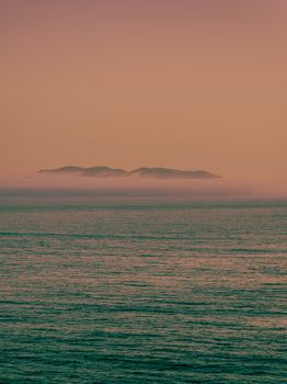 Serene view of misty island during sunrise over the calm ocean in Ireland.