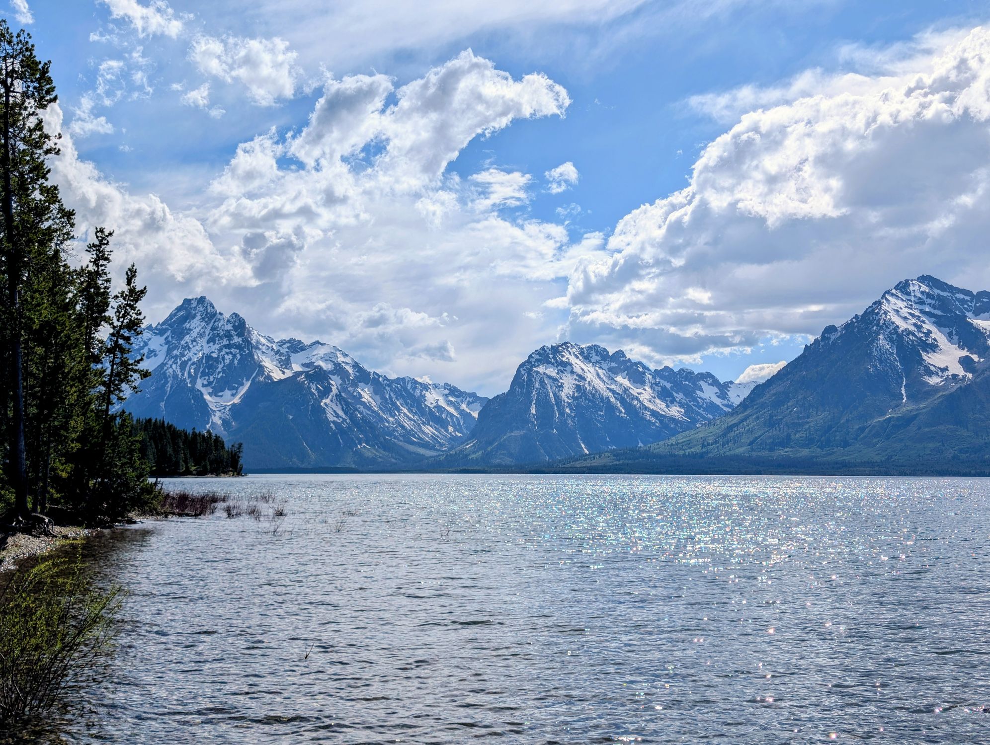 Capture of the Grand Teton mountains with a sparkling lake under a bright blue sky in Wyoming.