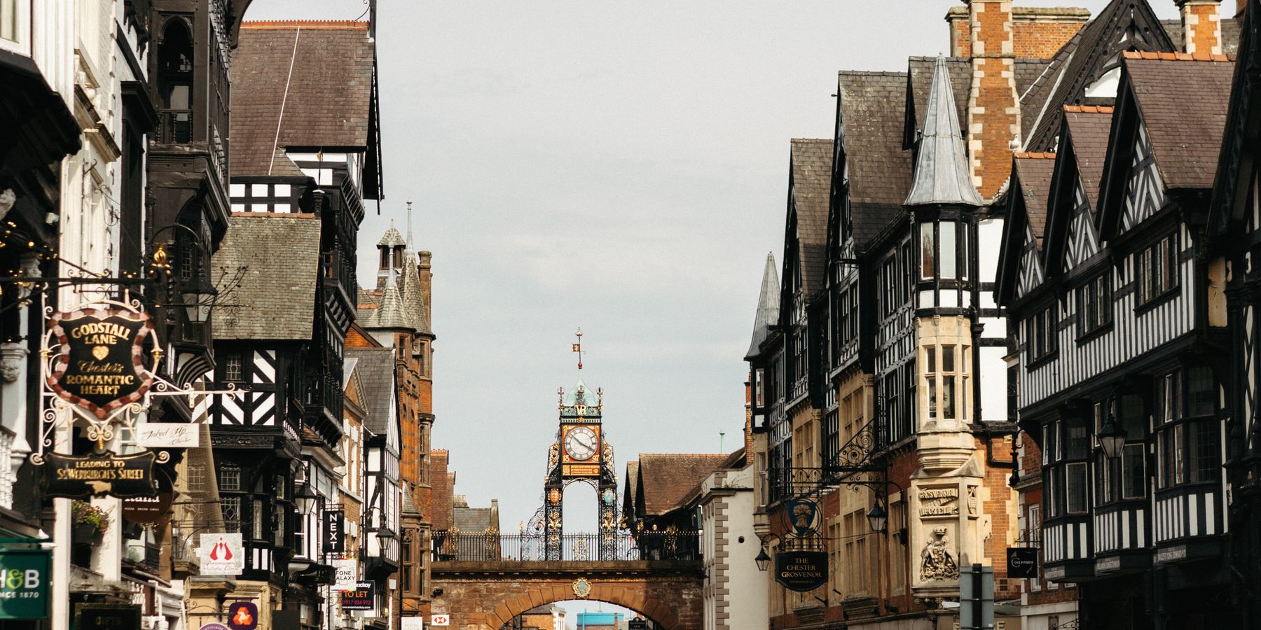 Busy street in Chester, England, featuring medieval architecture and the iconic Eastgate Clock.