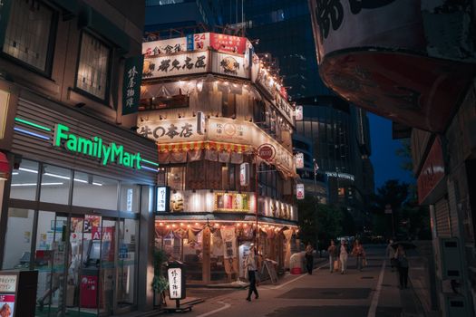 Tokyo street illuminated with neon signs and bustling nightlife, showcasing vibrant urban culture.