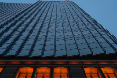 Free A towering glass skyscraper in Tokyo, Japan, with its facade illuminated at dusk, showcasing modern architecture. Stock Photo