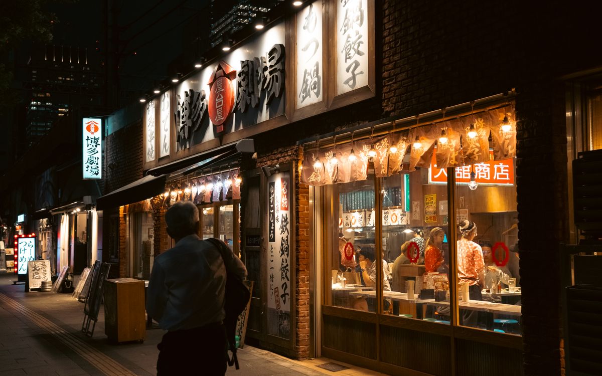 A traditional Japanese restaurant lit up on a Tokyo street at night