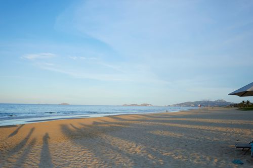 Free Tranquil beach view at sunset in Quy Nhon, Vietnam, ideal for relaxation and travel inspiration. Stock Photo