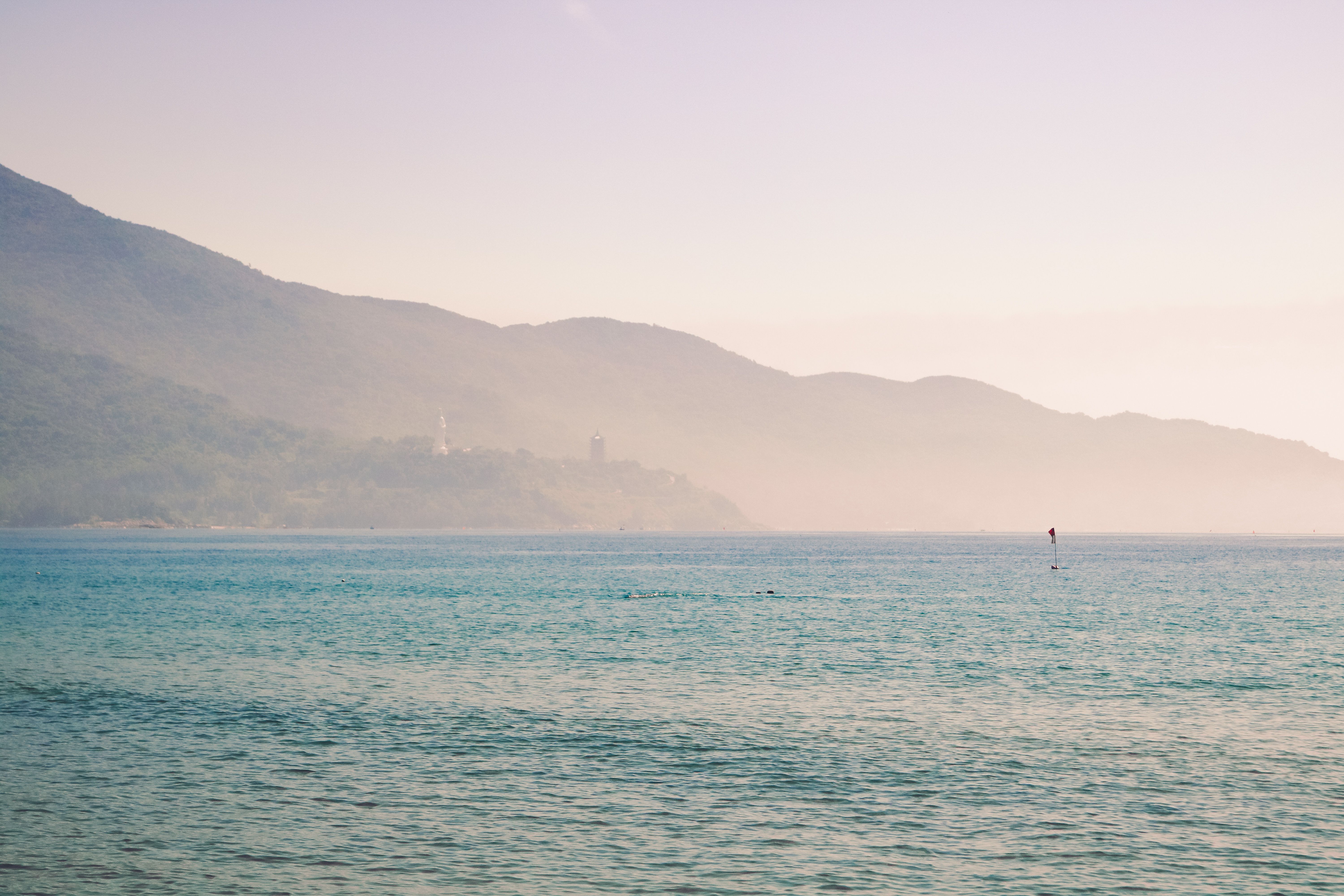 Peaceful scene of Vietnam's coastline with mountains in the background, captured at sunrise.
