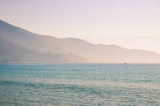 Peaceful scene of Vietnam's coastline with mountains in the background, captured at sunrise.