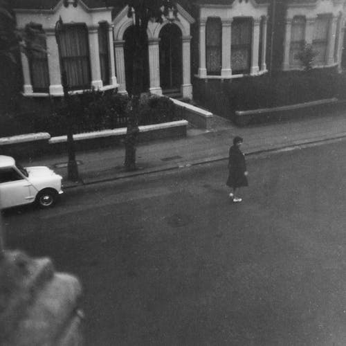 Grayscale Photo of Woman Walking on Street