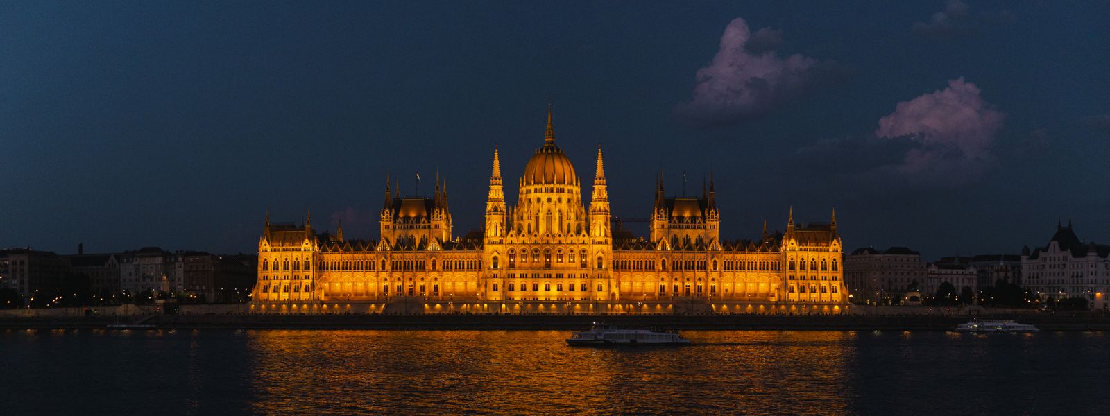 Night view of the glowing Hungarian Parliament Building reflected in the Danube River.