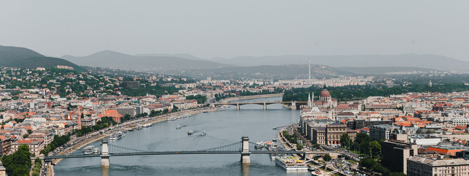 A stunning aerial photograph of Budapest featuring the Chain Bridge spanning the Danube River with cityscape views.