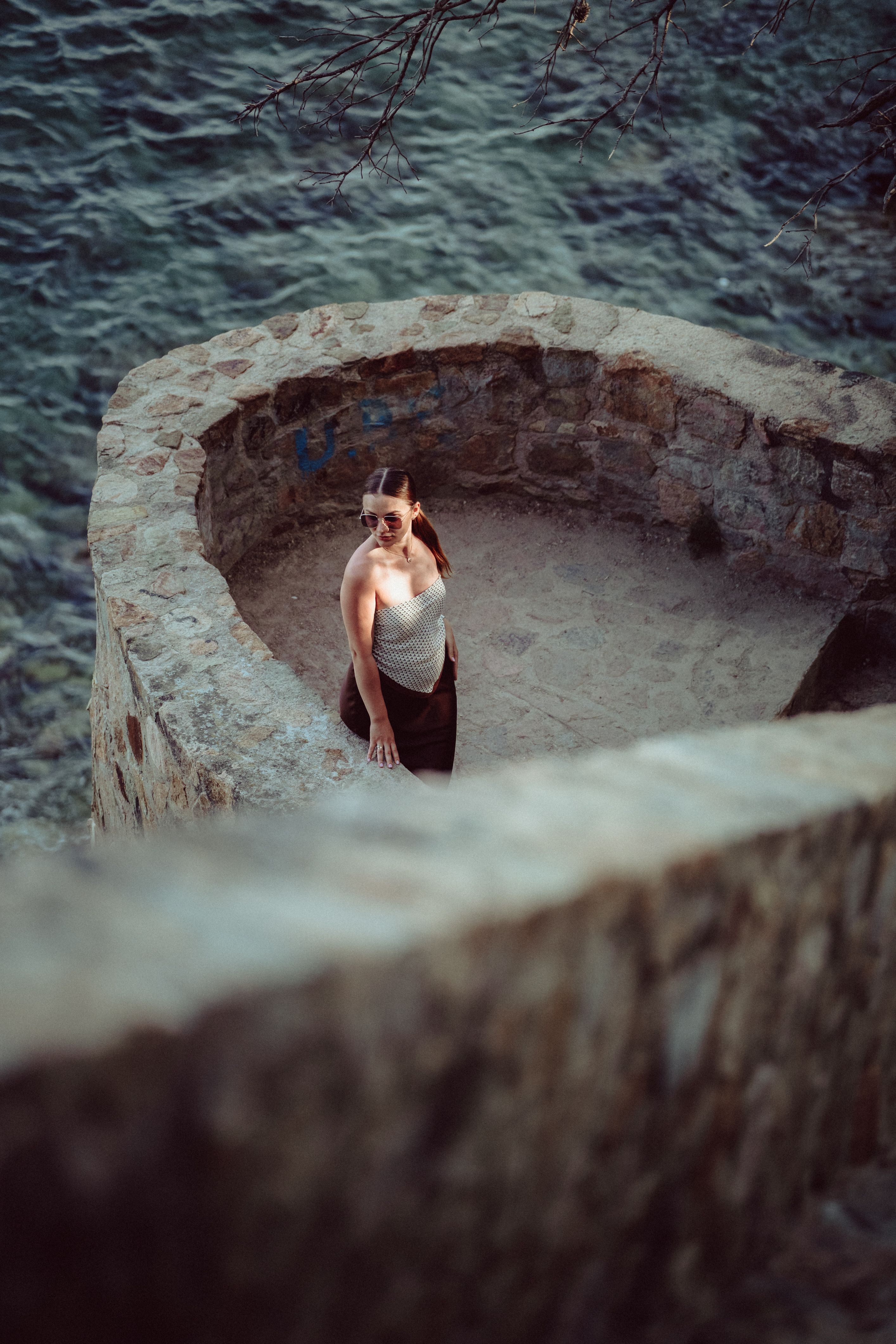 Young woman standing in a stone circular structure overlooking the sea in Lloret de Mar, Spain.