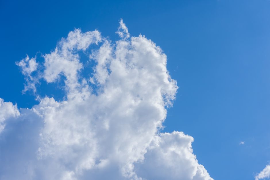 A serene, minimalist view of fluffy white clouds against a clear blue sky in Valencia, Spain.