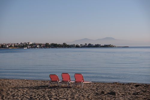Free Tranquil beach view in Foça, İzmir with empty lounge chairs facing the sea during daytime. Stock Photo