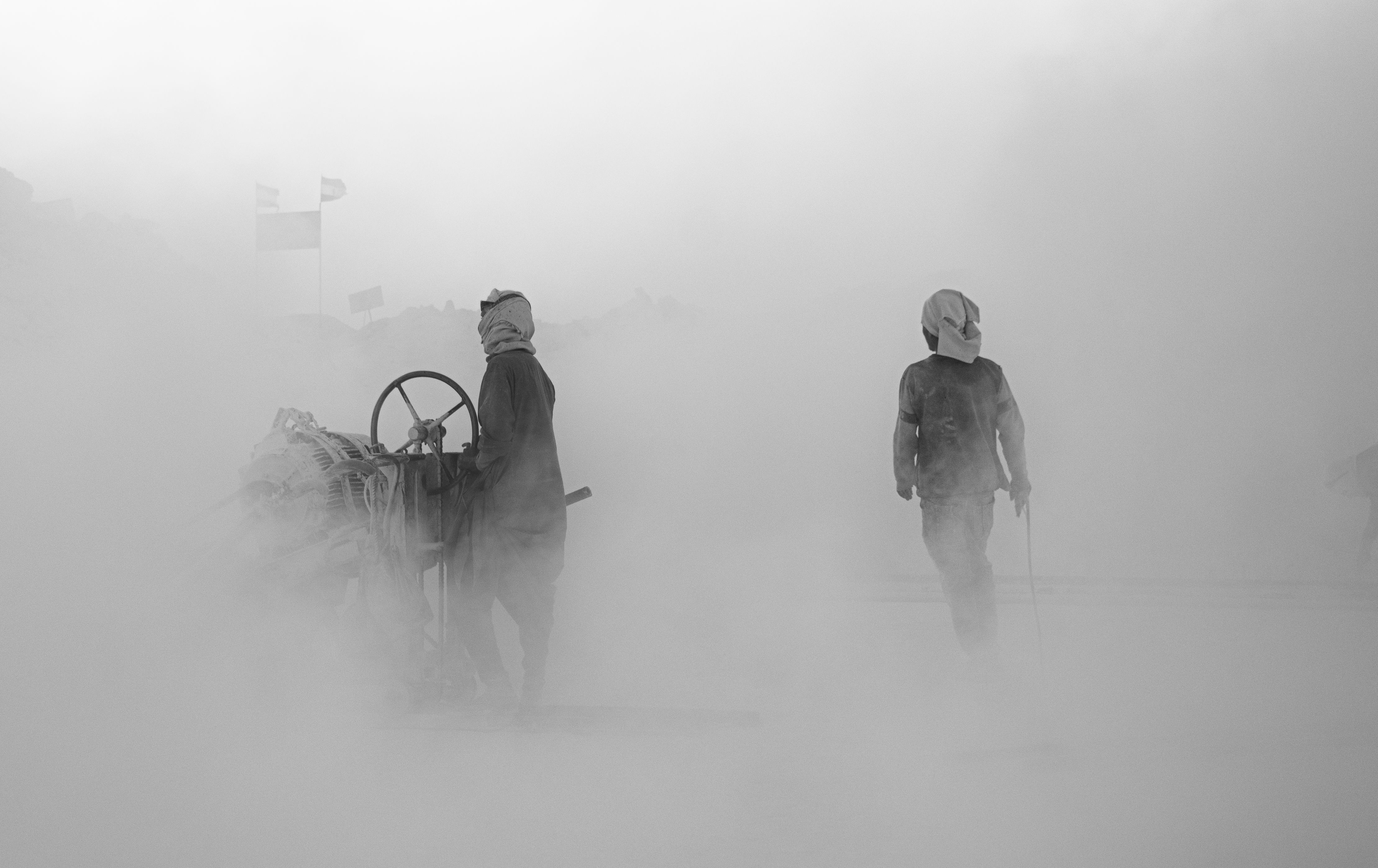 Two workers in dusty conditions at a site in Minya, Egypt, illustrating industrial labor.