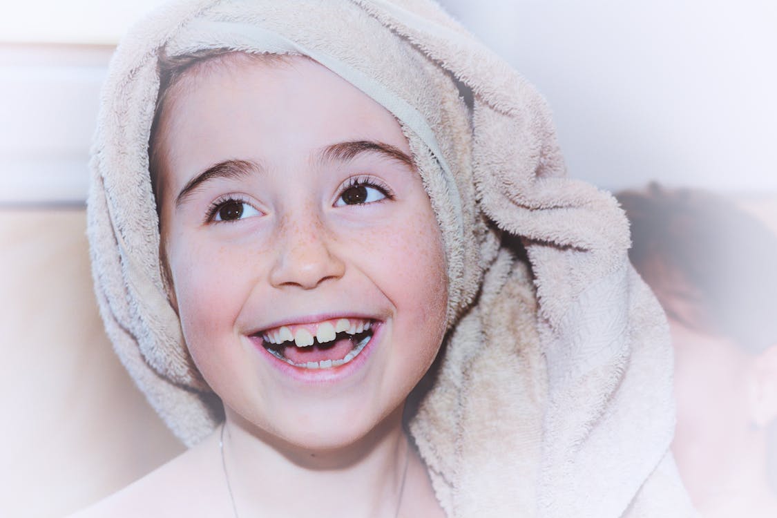 Person Wearing Beige Bath Towel on Head While Smiling