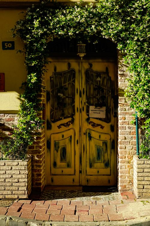 Free Rustic yellow doors framed by ivy and brick, evoking charm and history. Stock Photo