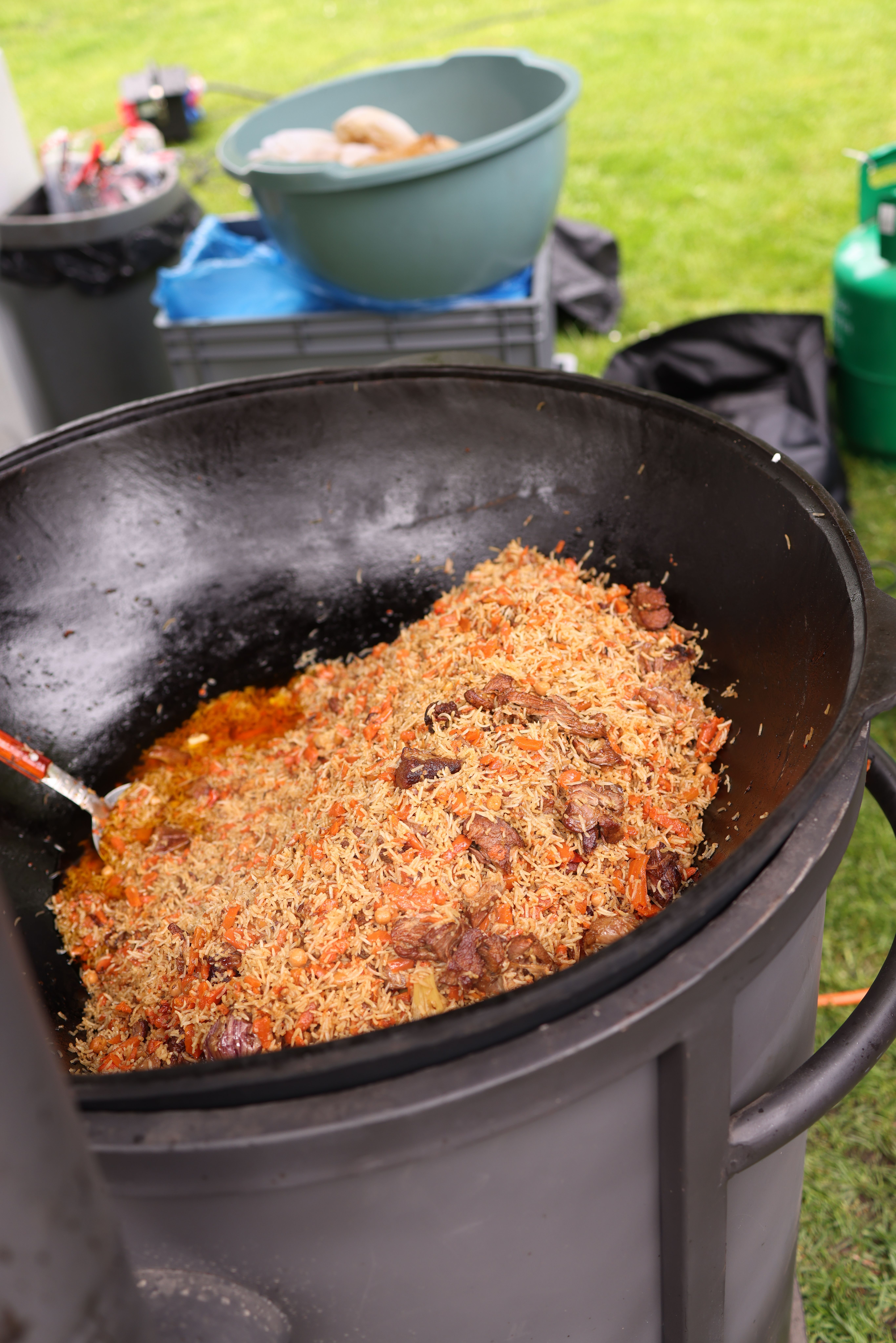 A large pot of seasoned rice and meat cooking outdoors. Perfect for communal gatherings.