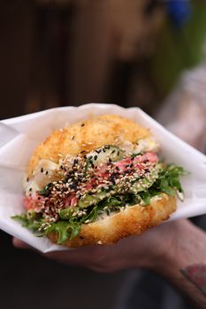 Close-up of a rice burger with fresh greens and sesame seeds.