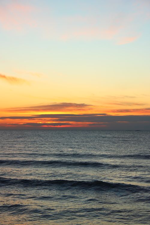 Free Stunning ocean sunset with colorful sky reflecting on the peaceful water surface. Stock Photo