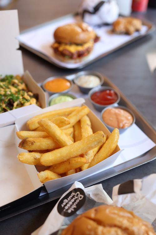 Free A tray of golden fries and burgers with assorted sauces at a casual dining spot. Stock Photo