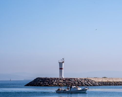 Free Peaceful scene of a boat near a lighthouse at Foça harbor, İzmir, Türkiye. Stock Photo