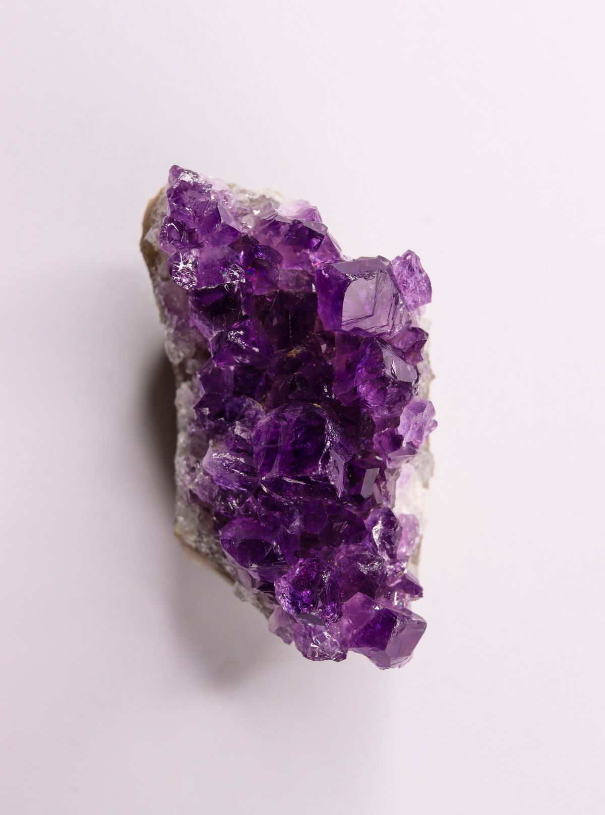 Raw amethyst crystal cluster on a lilac background