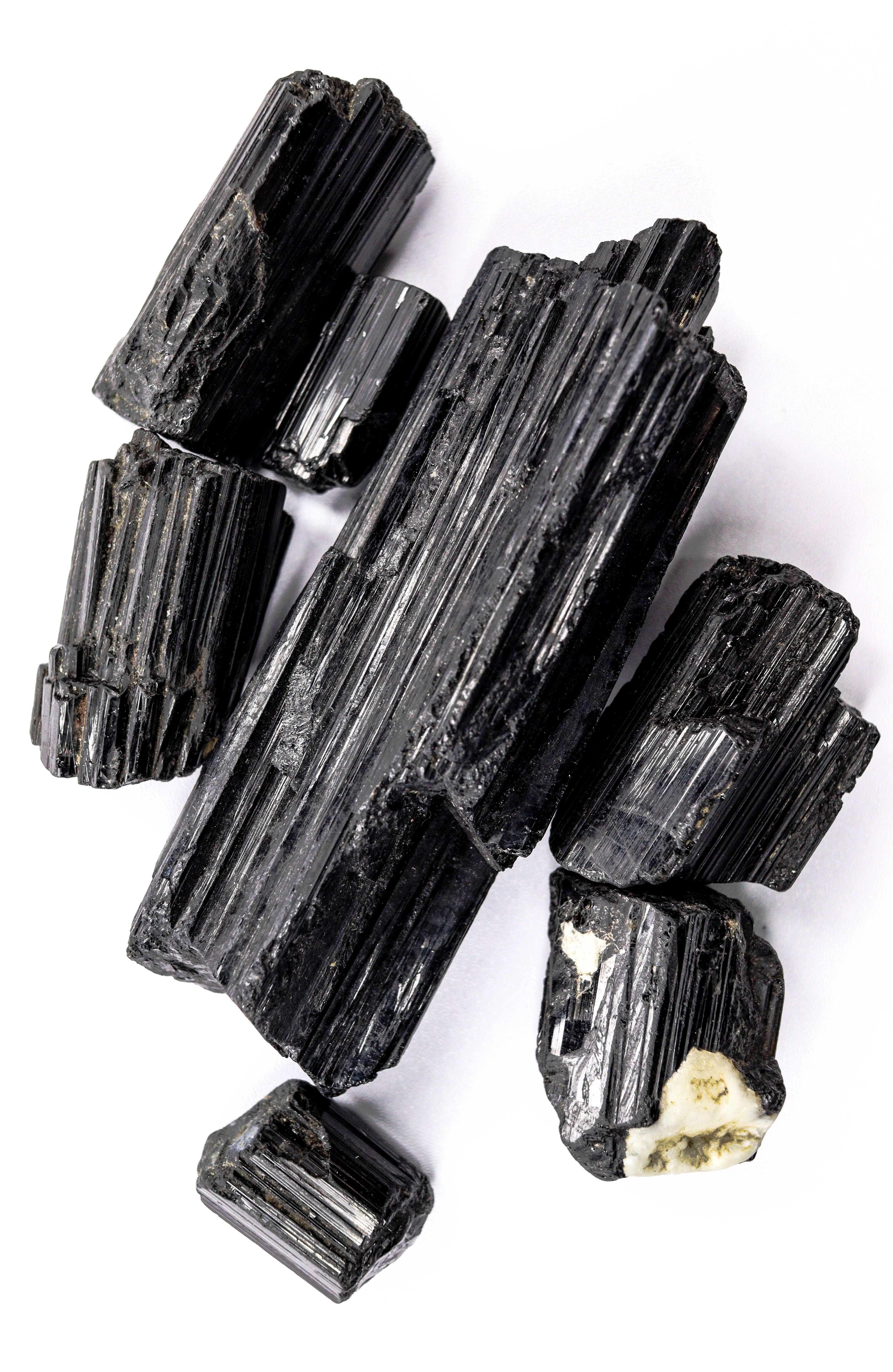 Black tourmaline crystals arranged on a clean white surface, showcasing their natural texture and shine.