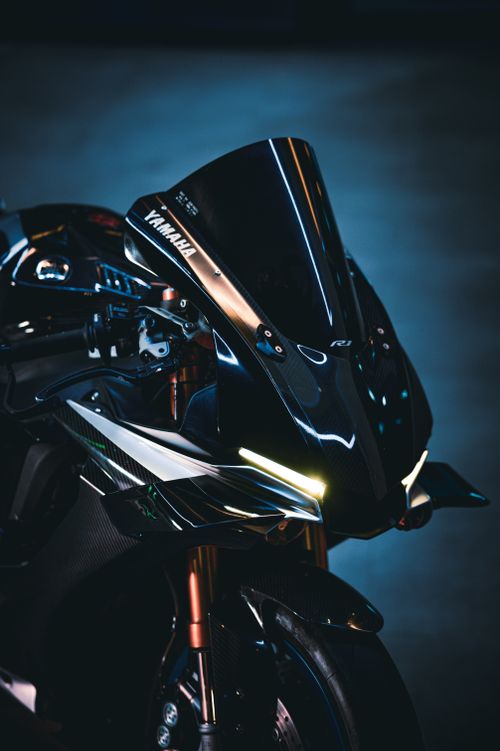 Free Close-up of a modern black sport motorcycle with neon lights against a dark background. Stock Photo