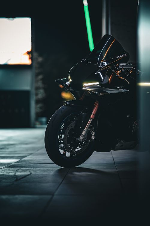 Free A stylish black motorcycle parked outdoors at night, accentuated by its sleek design under urban lights. Stock Photo
